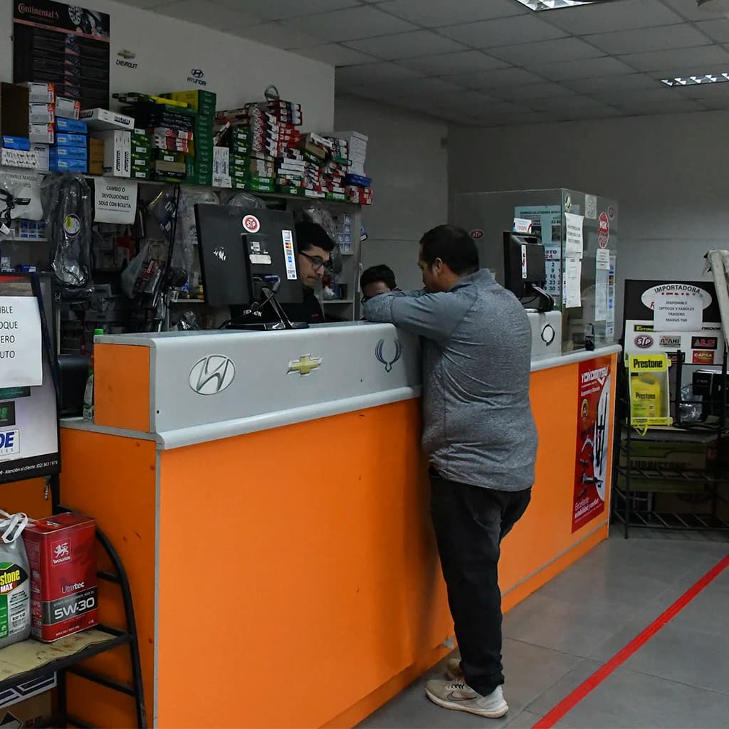 Vendedor de Repuestos Automotrices JFNN asesorando a un cliente en el mostrador de Melipilla
